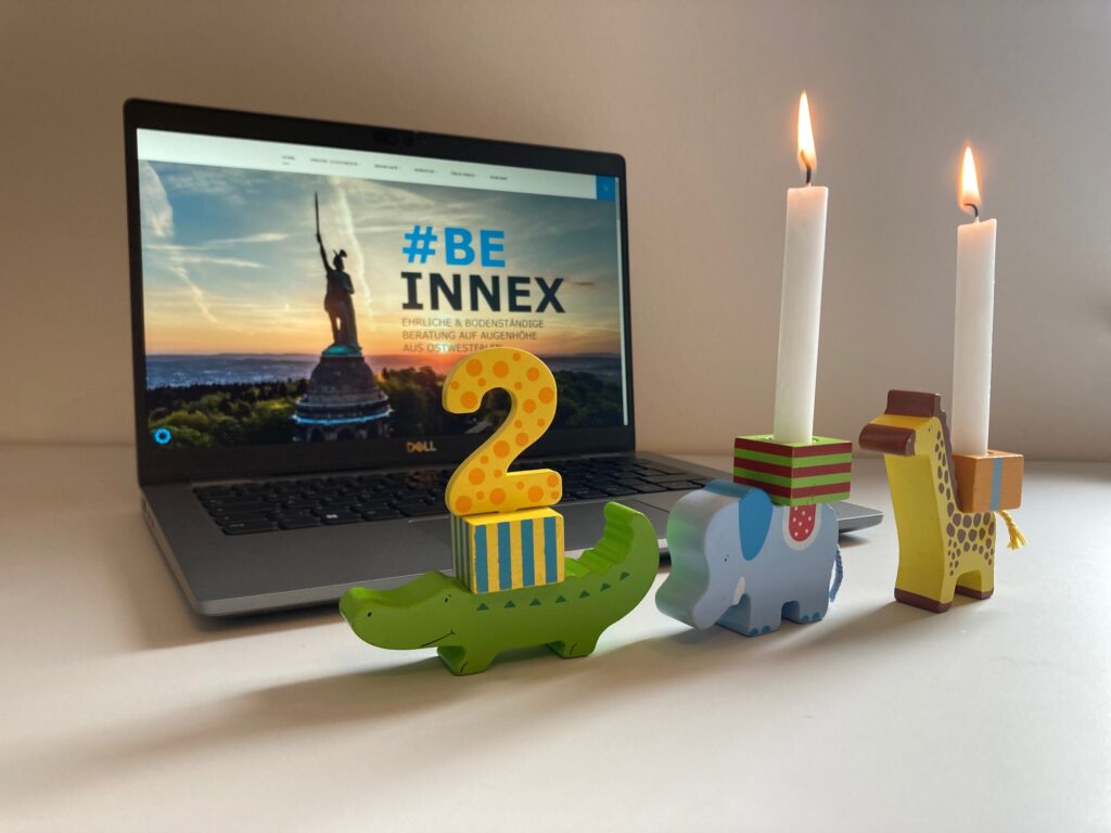Kindergeburtstagskerzen zum zweiten Geburtstag von INNEX vor einem Laptop, der die INNEX Website zeigt
